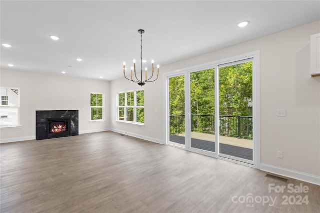 unfurnished living room featuring hardwood / wood-style flooring, a chandelier, and a fireplace