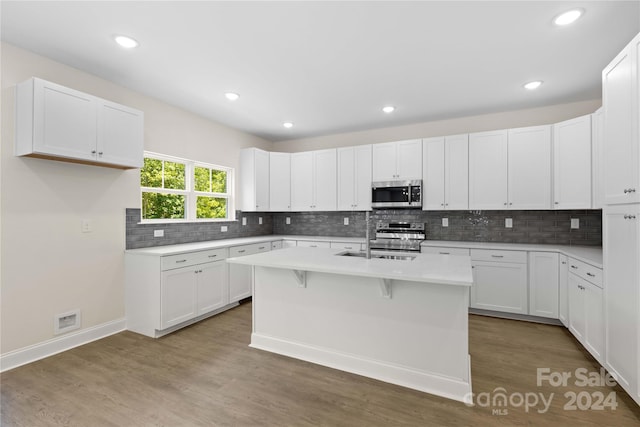 kitchen with dark hardwood / wood-style floors, sink, white cabinets, a kitchen island with sink, and stainless steel appliances