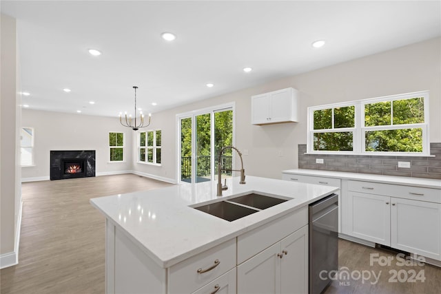 kitchen featuring dishwasher, an island with sink, sink, white cabinetry, and light stone countertops