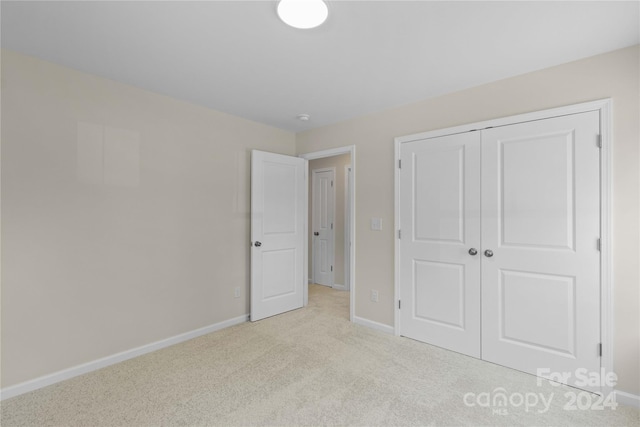 unfurnished bedroom with light colored carpet and a closet