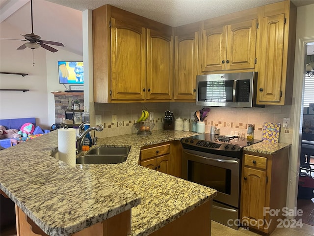 kitchen with appliances with stainless steel finishes, decorative backsplash, light stone counters, and sink