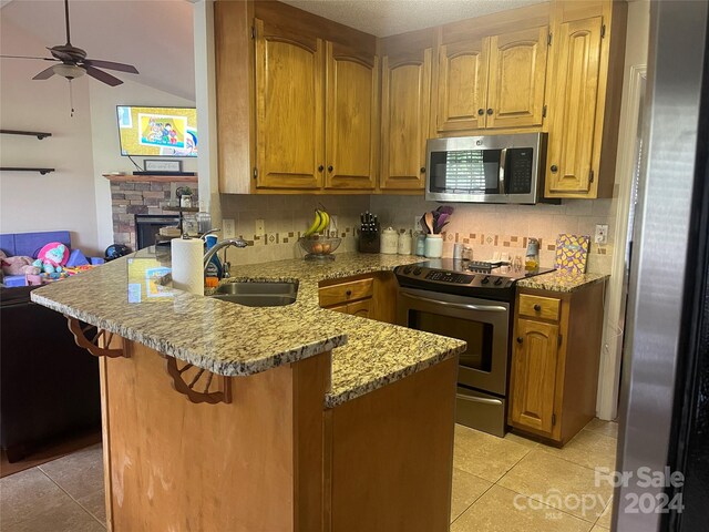 kitchen with light tile patterned floors, sink, appliances with stainless steel finishes, and kitchen peninsula