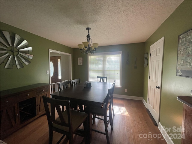 dining area with dark hardwood / wood-style floors, a chandelier, and a textured ceiling