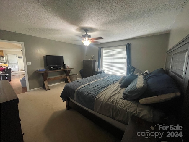 carpeted bedroom featuring ceiling fan and a textured ceiling