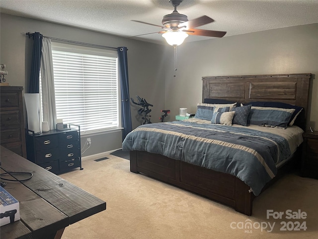 bedroom featuring a textured ceiling, ceiling fan, and light colored carpet