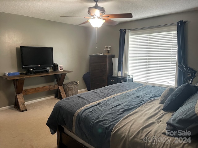 carpeted bedroom with ceiling fan and a textured ceiling