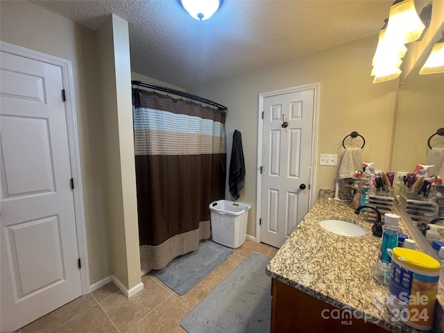 bathroom with a textured ceiling, tile patterned floors, and vanity