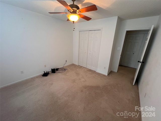 unfurnished bedroom with ceiling fan, light colored carpet, and a closet