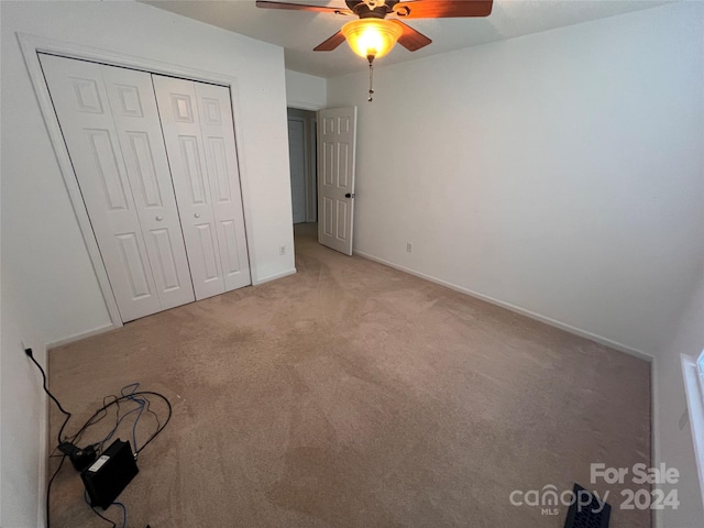 unfurnished bedroom featuring ceiling fan, light colored carpet, and a closet