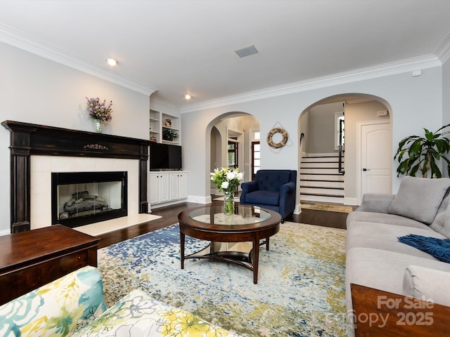 living room featuring built in shelves, ornamental molding, and dark hardwood / wood-style floors