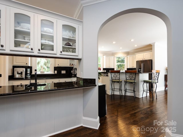 kitchen with high end refrigerator, white cabinets, dark hardwood / wood-style flooring, backsplash, and crown molding