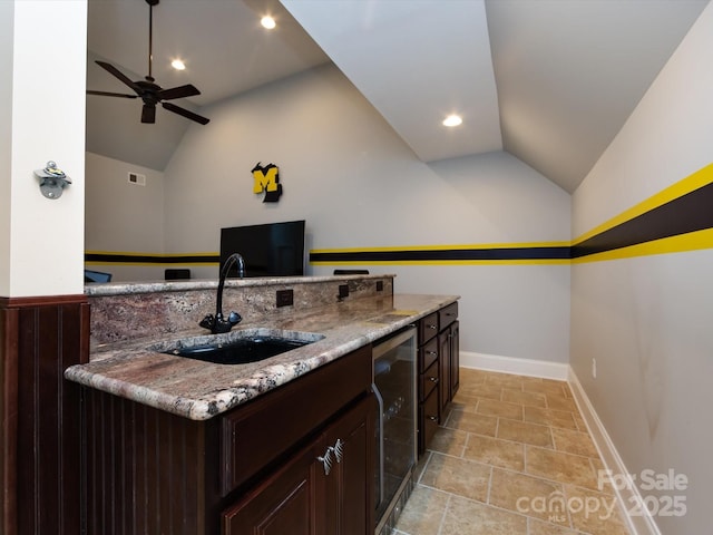 kitchen featuring lofted ceiling, sink, wine cooler, a kitchen island with sink, and light stone counters