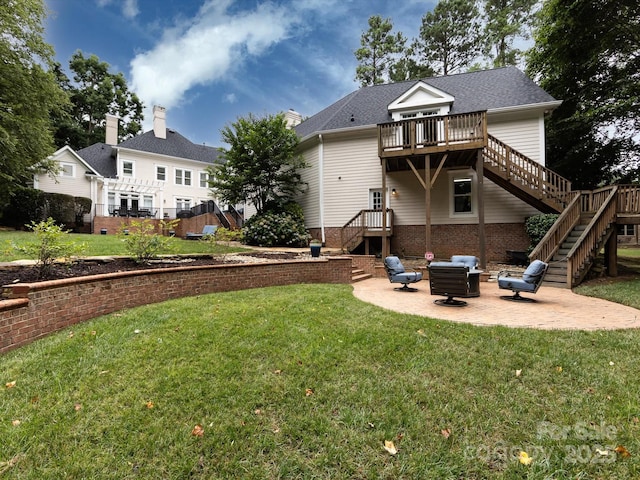 rear view of property featuring a wooden deck, a patio, a yard, and a fire pit