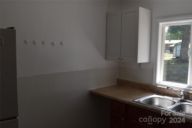 kitchen with white cabinets, sink, white fridge, and dark brown cabinets