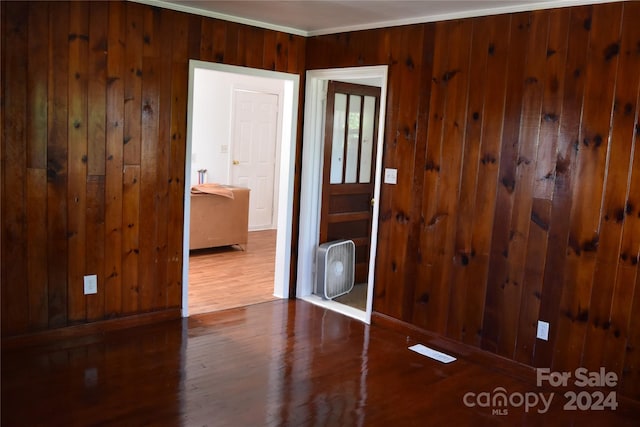 spare room featuring wood walls, ornamental molding, and hardwood / wood-style flooring