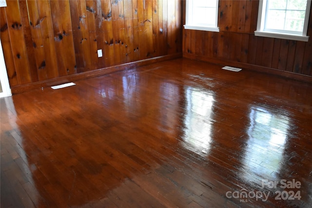 spare room featuring wooden walls and dark wood-type flooring