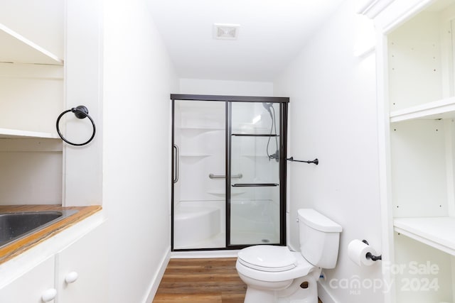 bathroom featuring hardwood / wood-style floors, an enclosed shower, and toilet