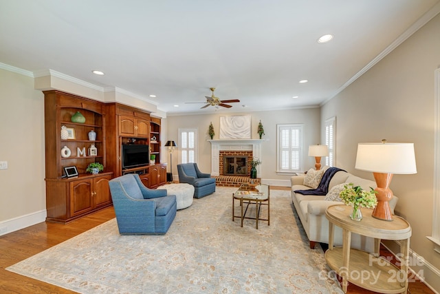 living room featuring light wood-type flooring, crown molding, a wealth of natural light, and a brick fireplace