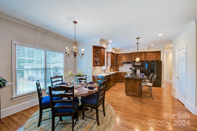 dining space featuring crown molding, sink, light hardwood / wood-style flooring, and a notable chandelier