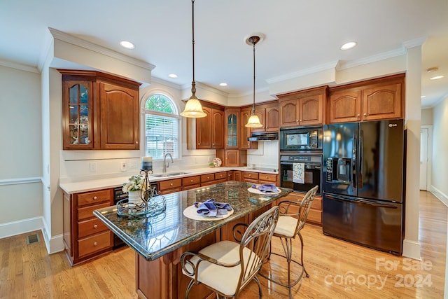 kitchen featuring sink, decorative light fixtures, decorative backsplash, a kitchen island, and black appliances