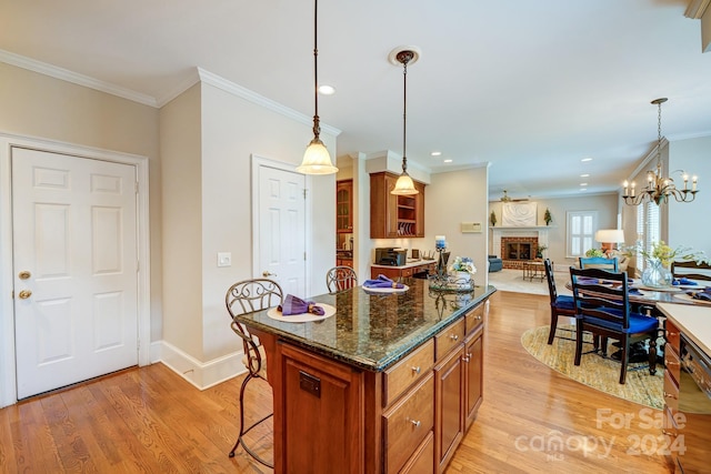 kitchen with a fireplace, a center island, hanging light fixtures, and crown molding