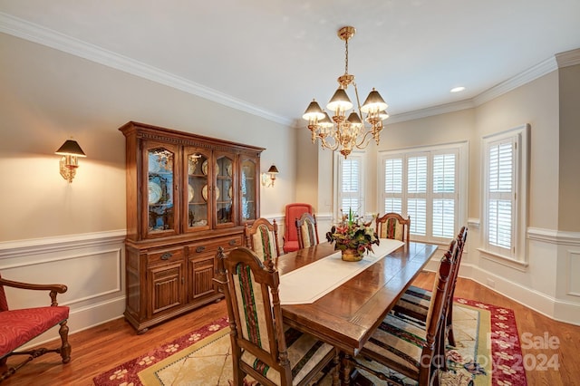 dining space featuring light hardwood / wood-style floors, ornamental molding, and an inviting chandelier