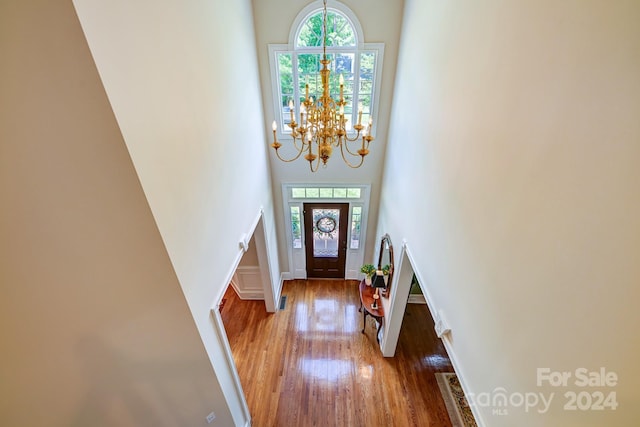 entrance foyer featuring hardwood / wood-style floors, a towering ceiling, plenty of natural light, and a notable chandelier