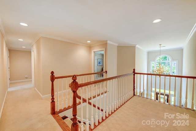 hall with a chandelier, crown molding, and light colored carpet