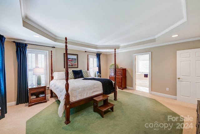 bedroom featuring light colored carpet, a raised ceiling, ensuite bath, and crown molding