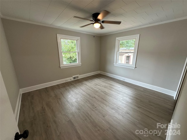 unfurnished room featuring a healthy amount of sunlight, ornamental molding, dark wood-type flooring, and ceiling fan