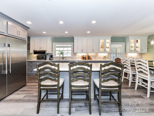 kitchen with hardwood / wood-style floors, white cabinets, a breakfast bar area, appliances with stainless steel finishes, and sink