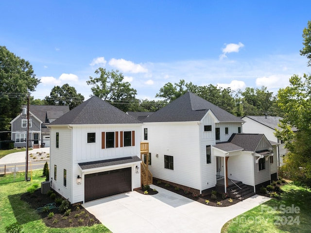 modern inspired farmhouse featuring a garage, concrete driveway, board and batten siding, and roof with shingles