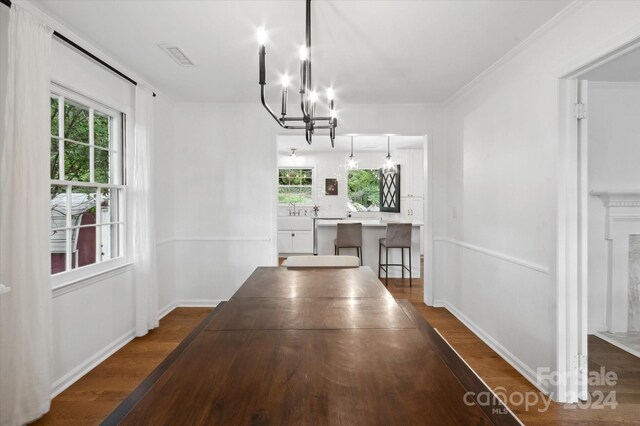 unfurnished dining area featuring hardwood / wood-style flooring, a healthy amount of sunlight, and a chandelier