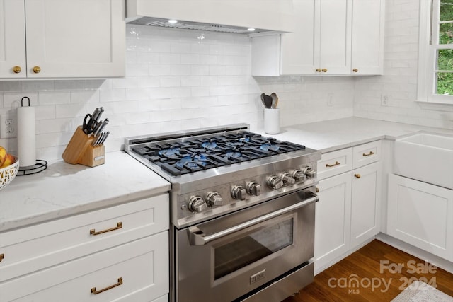 kitchen featuring tasteful backsplash, high end stainless steel range, white cabinets, and custom exhaust hood