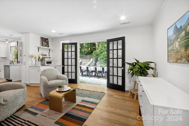 living room featuring light hardwood / wood-style flooring, ornamental molding, and french doors