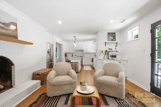 living room featuring brick wall, light wood-type flooring, and a fireplace