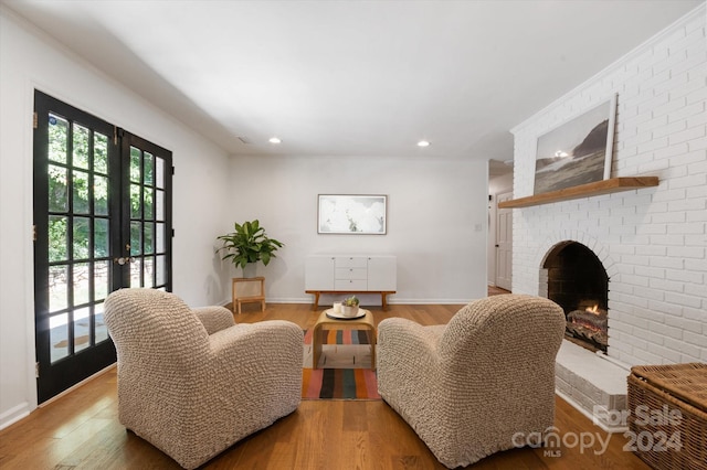 living room featuring a fireplace, light hardwood / wood-style floors, and french doors