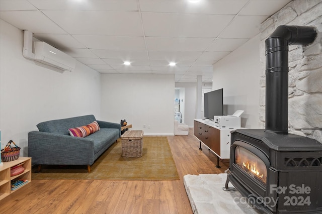 living room with light hardwood / wood-style flooring, a wall mounted AC, and a wood stove