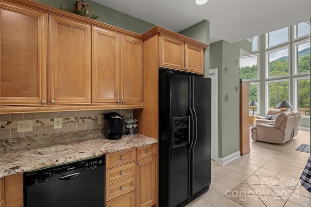 kitchen with light tile patterned floors, backsplash, light stone counters, and black appliances