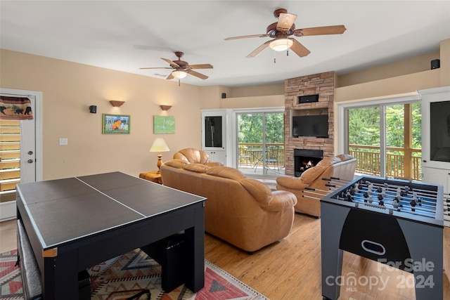 rec room featuring ceiling fan, a fireplace, and light hardwood / wood-style flooring