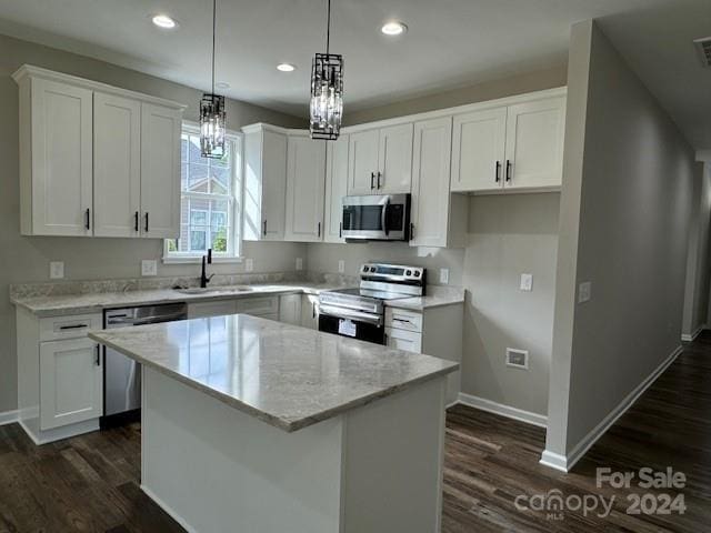 kitchen with white cabinets, appliances with stainless steel finishes, a center island, decorative light fixtures, and sink