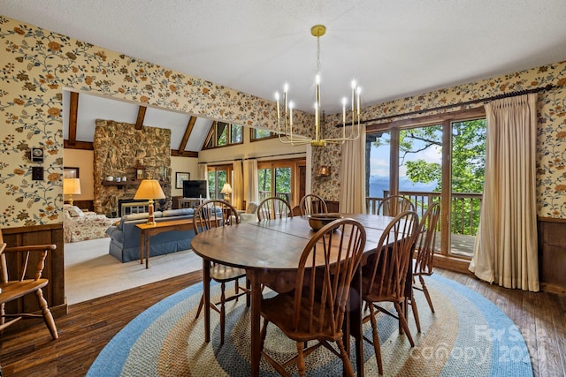 dining room with a notable chandelier, dark wood-type flooring, a fireplace, a textured ceiling, and lofted ceiling with beams