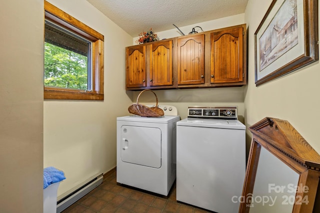 washroom with a baseboard heating unit, dark tile patterned flooring, cabinets, washer and dryer, and a textured ceiling