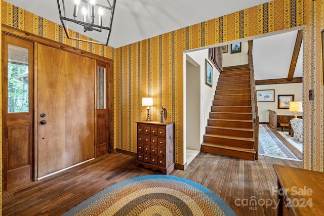 foyer featuring dark hardwood / wood-style floors, lofted ceiling, and a chandelier