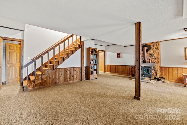 unfurnished living room featuring a textured ceiling, carpet, and a wood stove