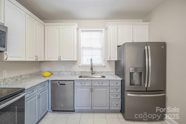 kitchen with sink, white cabinetry, gray cabinetry, stainless steel appliances, and light stone counters