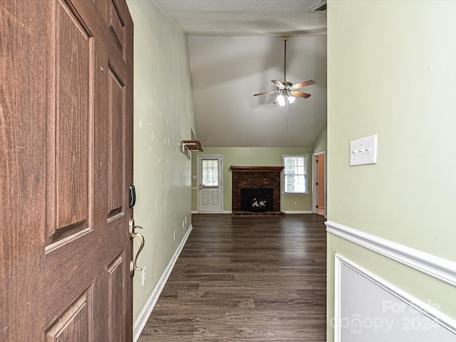 unfurnished living room featuring a fireplace, dark hardwood / wood-style flooring, ceiling fan, high vaulted ceiling, and a textured ceiling