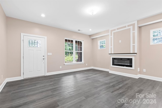 unfurnished living room with dark hardwood / wood-style flooring and a wealth of natural light