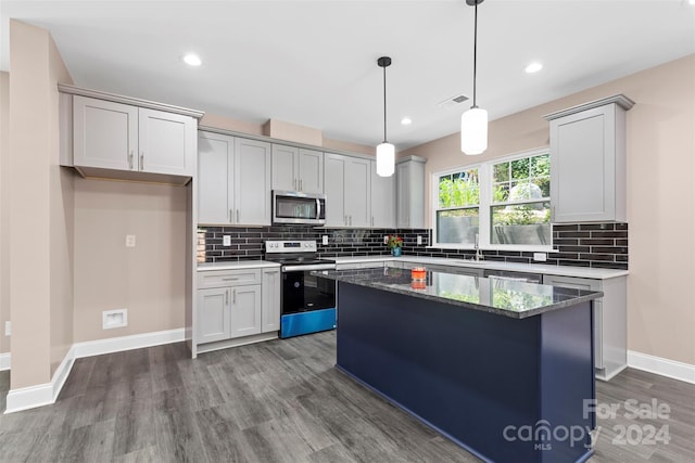 kitchen featuring dark hardwood / wood-style floors, stainless steel appliances, decorative light fixtures, and a kitchen island