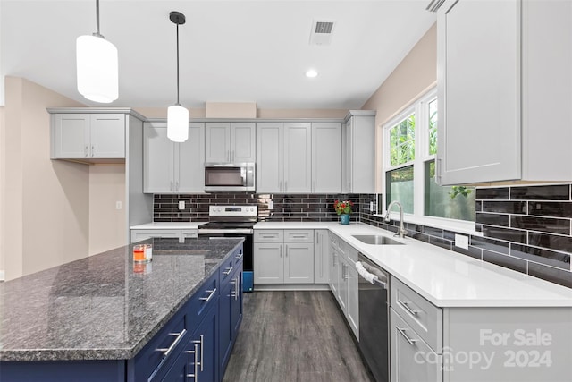 kitchen featuring appliances with stainless steel finishes, sink, hanging light fixtures, blue cabinets, and dark hardwood / wood-style flooring